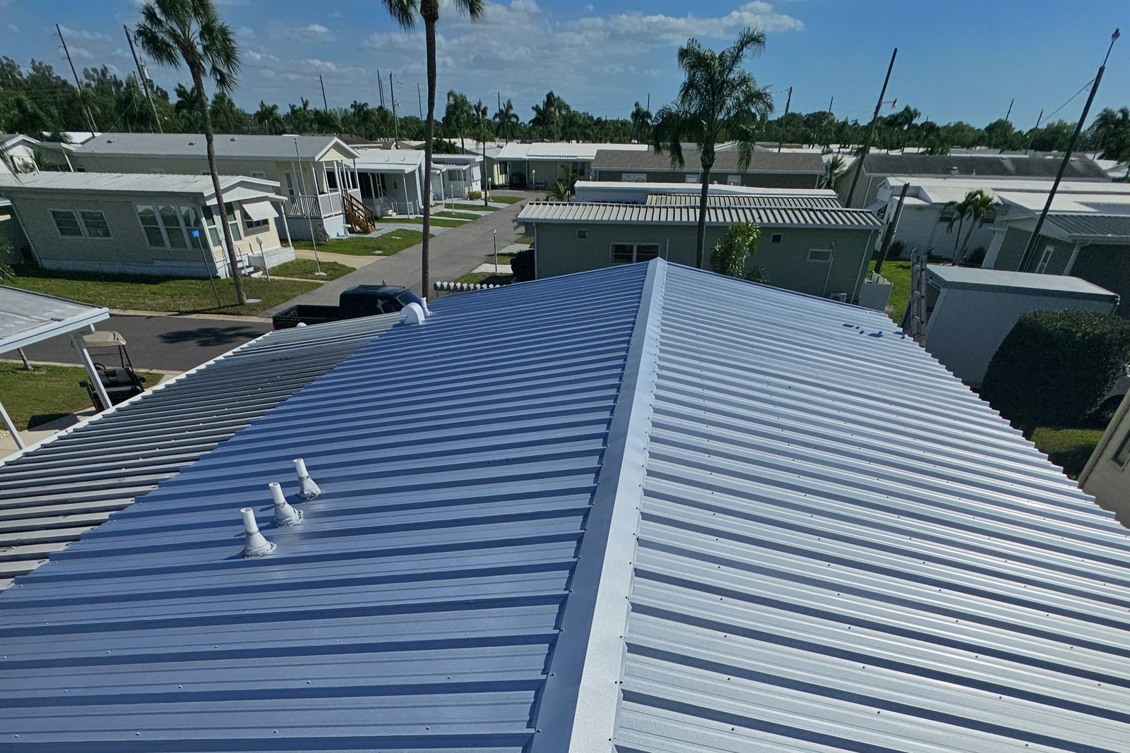 Finished ribbed metal roof with ridge cap and vent stacks on a Florida manufactured home